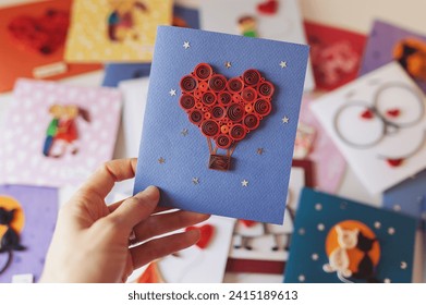 Hand holding quilling card with red heart balloon. Happy valentine day. woman making greeting cards. Hand made of paper quilling technique. Hobby, home office. Heart from red paper ribbons