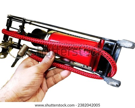 A hand holding a red and black air pump on white background. manual air pump.