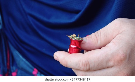 Hand Holding Red Metal Container Filled With Dried Herbs Close-Up Against Blue Background - Powered by Shutterstock