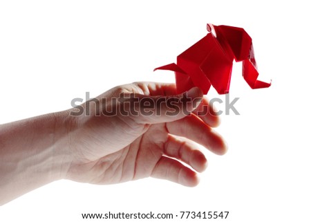 Hand holding a red paper origami elephant isolated over a white background.