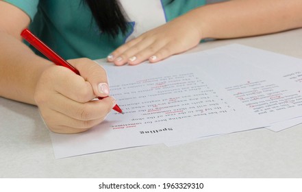 Hand Holding Red Pen Over Proofreading Paper On White Table