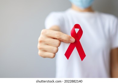 Hand holding Red Ribbon for December World Aids Day (acquired immune deficiency syndrome), multiple myeloma Cancer Awareness month and National Red ribbon week. Healthcare and world cancer day concept