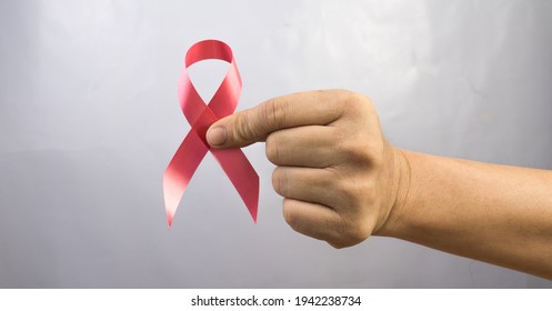 Hand Holding Red Ribbon On Black Background.
HIV Awareness Concept.
World AIDS Day 1 December.  Copy Space.