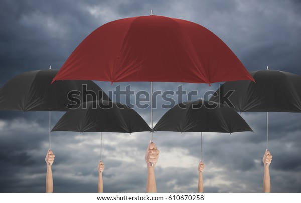 Hand holding red umbrella different among\
black umbellas. insurance policy life health protection of family\
conceptual.\
