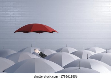 Hand holding a red umbrella on top of other white umbrellas. Business and safety concept