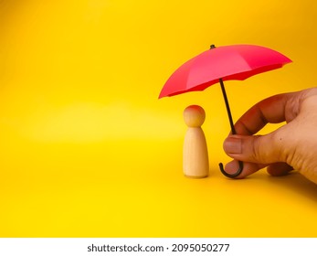 Hand holding red umbrella with peg doll on a yellow background.Insurance cover concept. - Shutterstock ID 2095050277