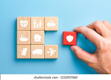 Hand holding red wooden blocks with insurance icons. family, life, car, travel, health and house insurance icons, blue background, Insurance concept 