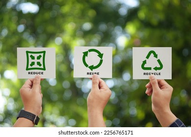 Hand holding reduce, reuse, recycle symbol on green bokeh background. Ecological and save the earth concept. An ecological metaphor for ecological waste management and a sustainable.