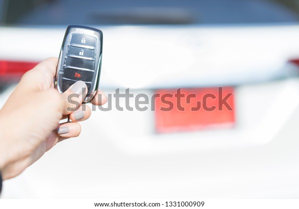 Hand holding remote car\
key.