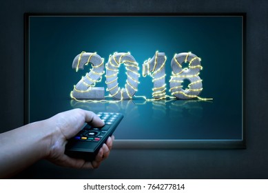 Hand holding remote controller with 2018 on TV screen. Happy New Year 2018
