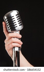  Hand Holding A Retro Microphone Over Black Background