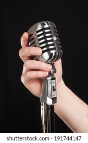  Hand Holding A Retro Microphone Over Black Background