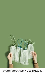 Hand holding reusable produce bags, diy from textile, reusable packaging for fruits and vegetables, mesh bag with ties, eco friendly and zero waste concept, flatlay on olive color background, top view