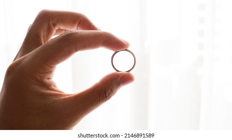 hand holding ring in front of window
