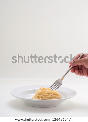 hand holding roll pasta spaghetti with a fork and bish on white background