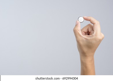 Hand Holding Round Lithium Button Cell Battery On White Background