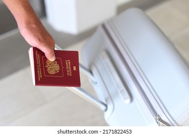 A hand holding Russian passport and suitcase  - Shutterstock ID 2171822453