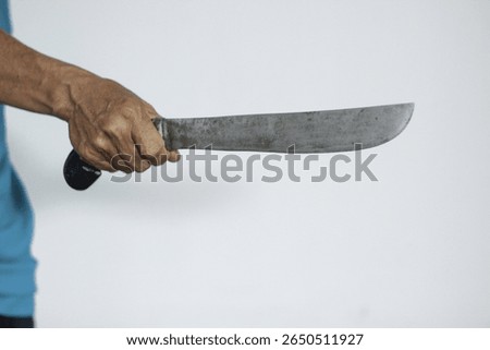 Hand holding a rustic, sharp machete. Symbolizes danger, violence, and aggression. Ideal for themes of crime, self-defense, or survival.