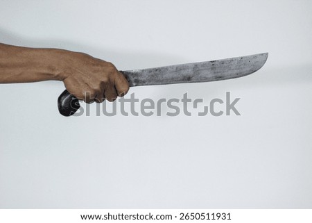 Hand holding a rustic, sharp machete. Symbolizes danger, violence, and aggression. Ideal for themes of crime, self-defense, or survival.