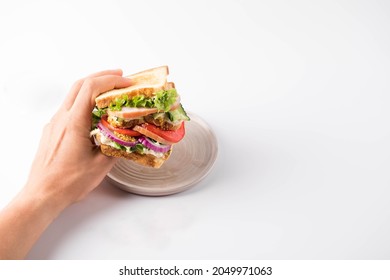 Hand Holding Sandwich With Ham, Tomato And Red Onion. Isolated On A White Background.