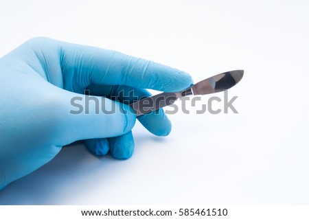 Hand holding scalpel. Palm of surgeon dressed in blue glove holding scalpel. Concept photo for surgeries, procedures, treatment, plastic surgery operation, work of surgical departments and hospitals