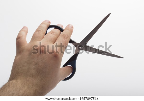 Hand is\
holding a scissors isolated on a white background. Stationery\
scissors in hand isolated on a white\
background.