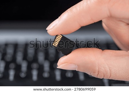 Hand holding sd memory card over laptop keyboard