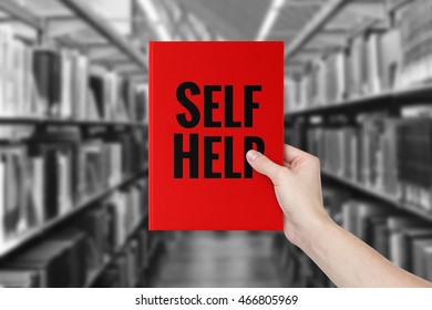 A hand holding 'Self-Help' book.