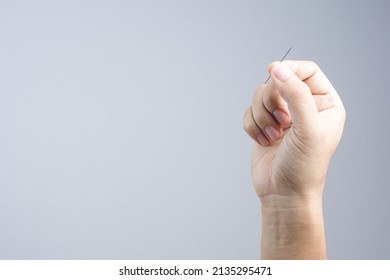 Hand Holding Sewing Needle On White Background
