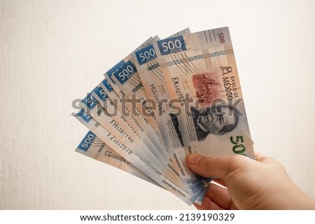 Hand holding and showing bills of five hundred Mexican pesos