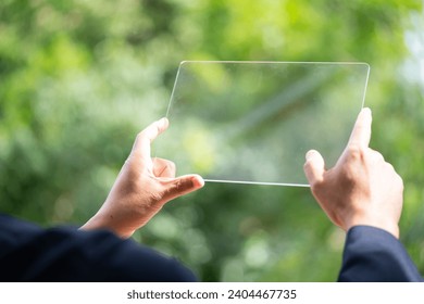 Hand holding and showing transparent tablet device. Business, natural green bokeh background,technology concept,alternative energy,conservative clean energy . - Powered by Shutterstock