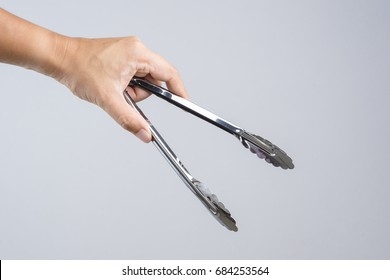 Hand holding silver serving kitchen tongs for picking food on white background