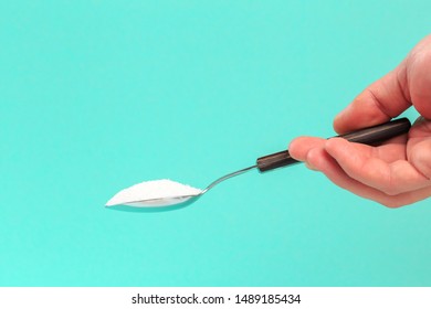 Hand Holding A Silver Spoon With Sugar 