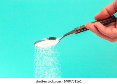 Hand Holding A Silver Spoon With Sugar 