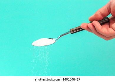 Hand Holding A Silver Spoon With Sugar 