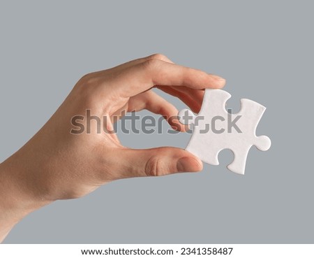 Hand holding single puzzle piece.