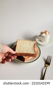 Hand Holding Slice Bread And Cup Of Coffee With Marshmallow On White Background. Morning Breakfast, Coffee Break. Tasty Beverage And Sweet Bakery. Winter And Autumn Concept