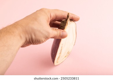 Hand holding sliced Purple eggplant with white stripes on pink pastel background. Side view, copy space. Tropical, healthy food, vegetable, minimalism. - Powered by Shutterstock