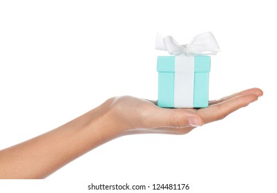 A Hand Holding A Small Blue Box With A White Ribbon In Its Palm Isolated On White.