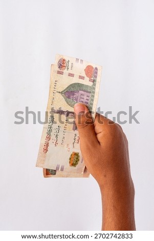 Hand holding a small stack of Egyptian 200 Pound banknotes vertically against a white background, perfect for concepts of payment, business, and financial transactions