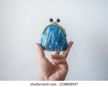 Hand Holding Small Vintage Coin Purse Made By Indigo Blue Fabric Isolated On White Background.