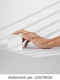 A Hand Holding A Small White Box On White Background With Shadows. Women Hand With Gold Ring