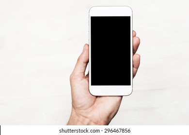 Hand Holding Smart Mobile Phone On Wooden Table And Light Blurred Background