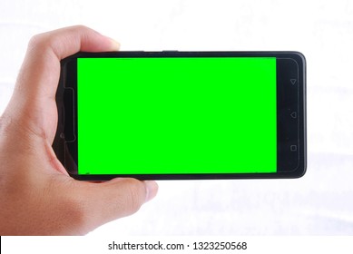 hand holding smart phone with green screen isolated on a white background

