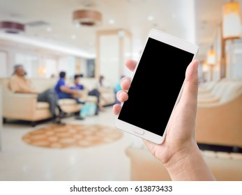 Hand Holding Smart Phone On Blurred Waiting Room At Hospital