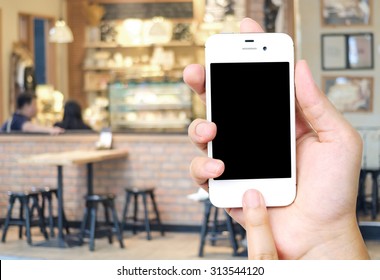 Hand Holding Smart Phone Over Blur Restaurant Background, Restaurant Reservation, Food Online, Food Delivery Concept