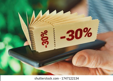 Hand Holding Smart Phone With Promo Code Coupons, Concept Of Mobile Phone Application And Shopping.