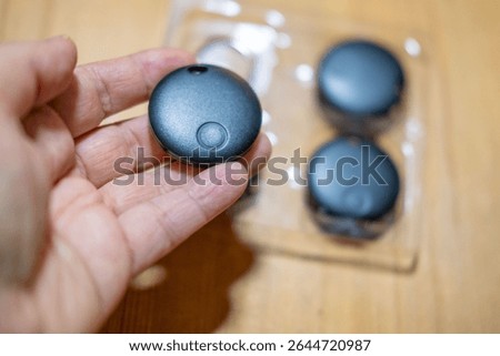 Hand holding smart tracker device, symbolizing personal item tracking and loss prevention, security and peace of mind through item tracking, personal tracking technology, lost items
