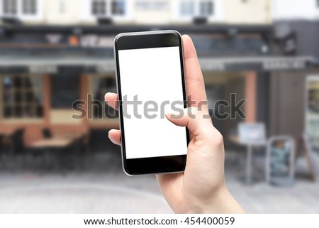 Hand holding smartphone in between buildings with shallow depth of field