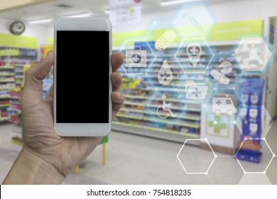 Hand Holding Smartphone With Black Blank Screen Over Blurred Pharmacy Interior Background With Modern Medical And Health Care Interface. For Product Display Montage.